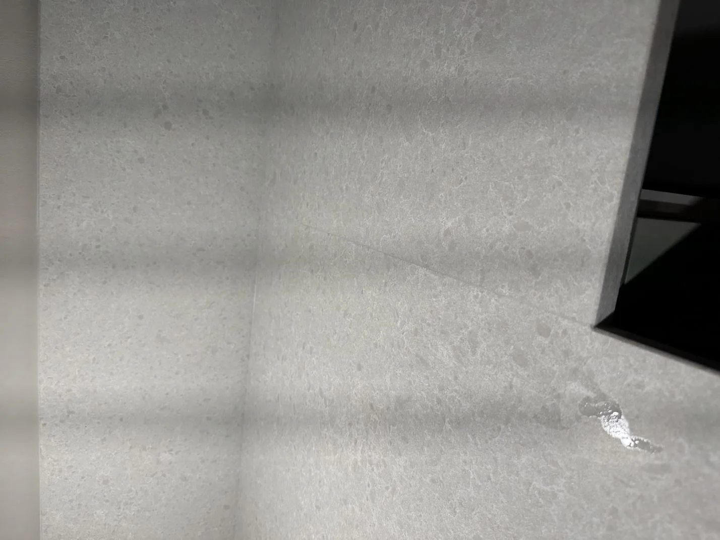 Detalj av hörn, bänkskiva och stänkskydd i Technistone Noble Quartzite, kvartskomposit med blandad matt och polerad finish, i Malmö.