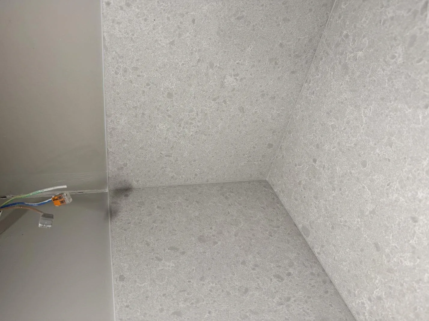 Närbild på stänkskydd och bänkskiva i Technistone Noble Quartzite, ljusgrå kvartskomposit med blandad matt och polerad finish, under montering i Malmö.