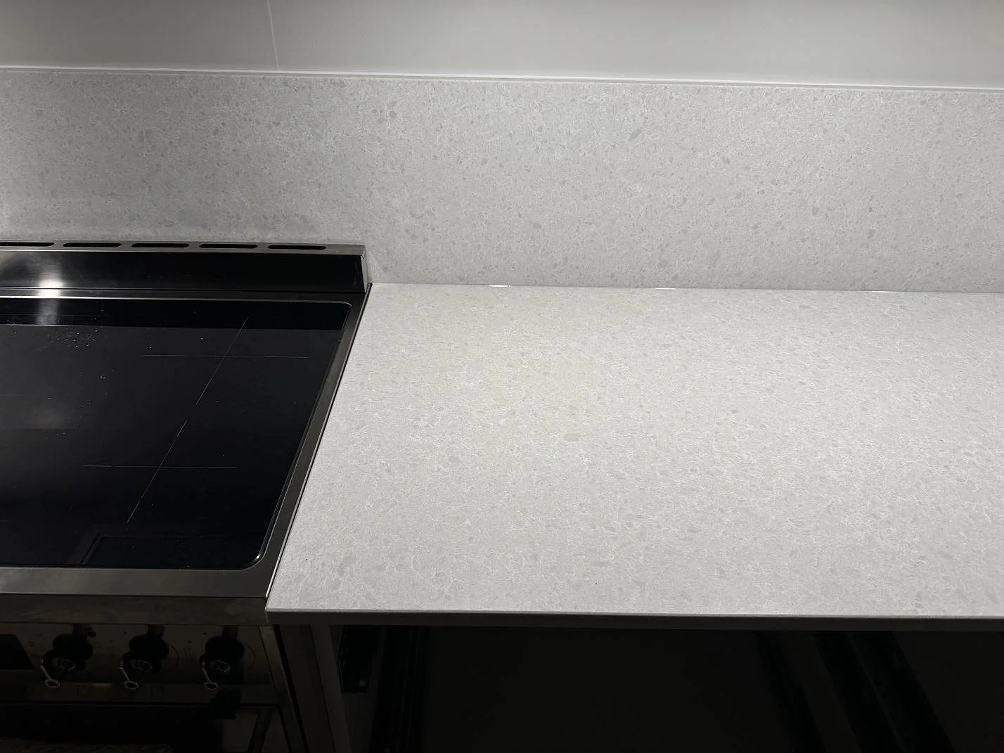 Köksbänk i Technistone Noble Quartzite, kvartskomposit med blandad matt och polerad finish, monterad med stänkskydd intill en fristående spis i Malmö.