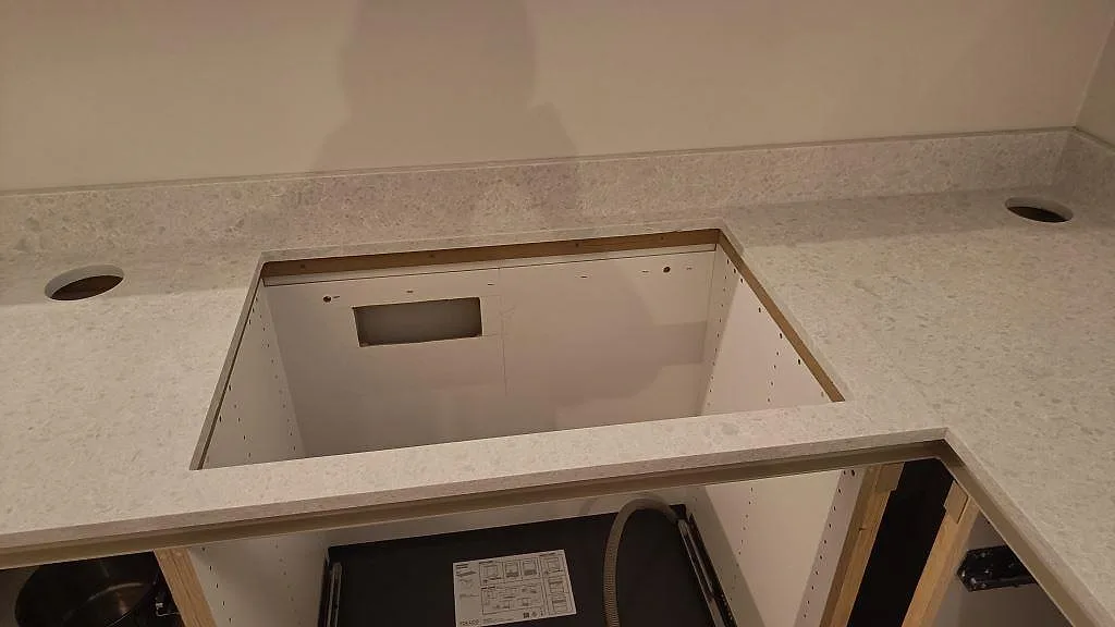 Rektangulärt urtag i köksbänkskiva av matt Technistone Noble Quartzite med stänkkant under montering i Malmö.