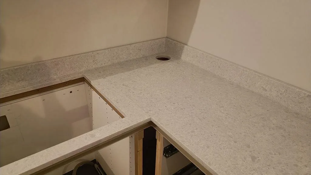 Hörnparti av köksbänkskiva i Technistone Noble Quartzite, matt ljus kvartskomposit, med låg stänkkant i Malmö.
