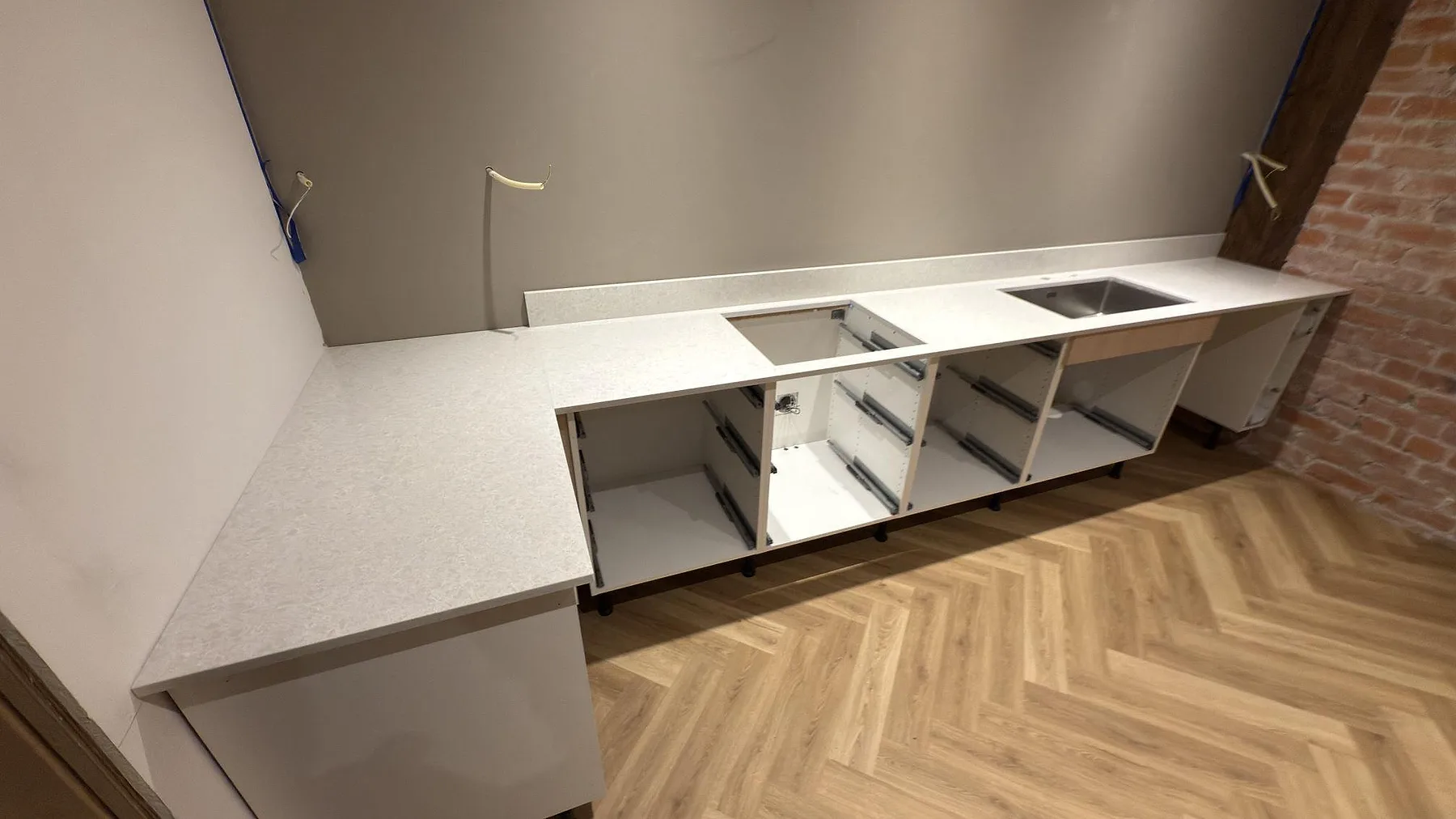 Polerad Technistone Noble Quartzite som köksbänkskiva i Mariefred, med lång arbetsyta, öppet urtag och uppvikt stänkkant under montering.