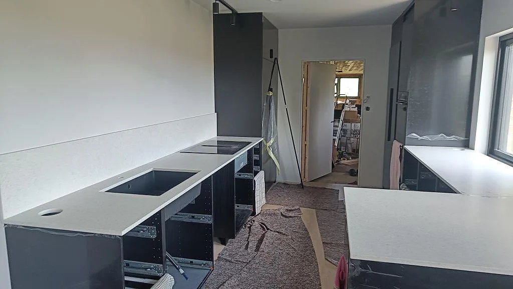 Köksbänkskiva i Technistone Noble Quartzite, matt kvartskomposit, med diskho, häll och stänkskydd under montering i Mölndal.