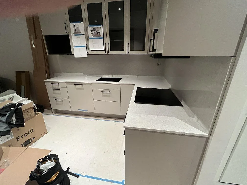 Köksbänkskiva i vit Technistone Noble Quartzite, polerad kvartskomposit, med häll i ett kök i Solna under montering.