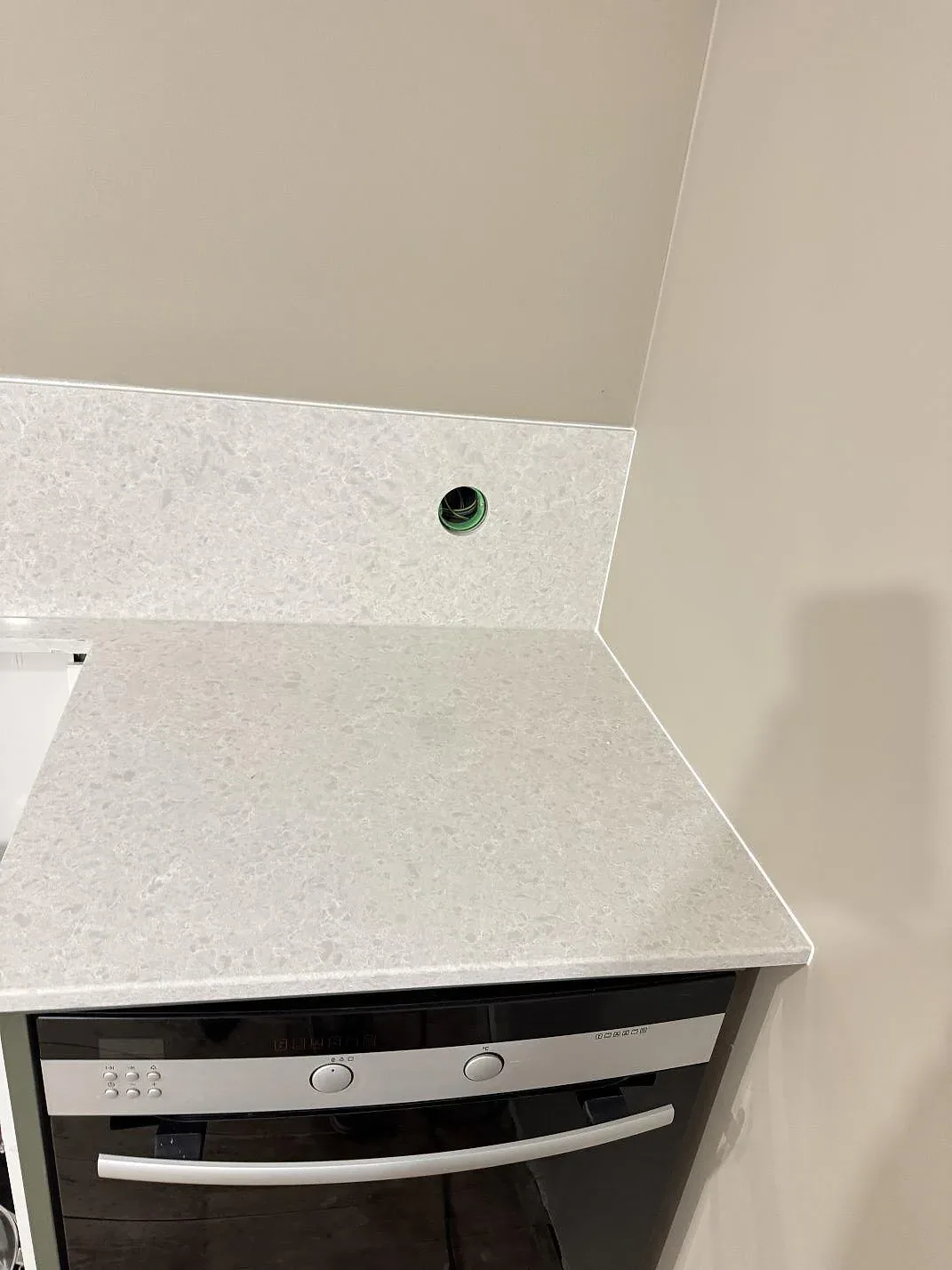 Köksbänk i Technistone Noble Quartzite med uppvikt stänkkant, polerad yta och öppning för vägguttag vid ugn i Staffanstorp.