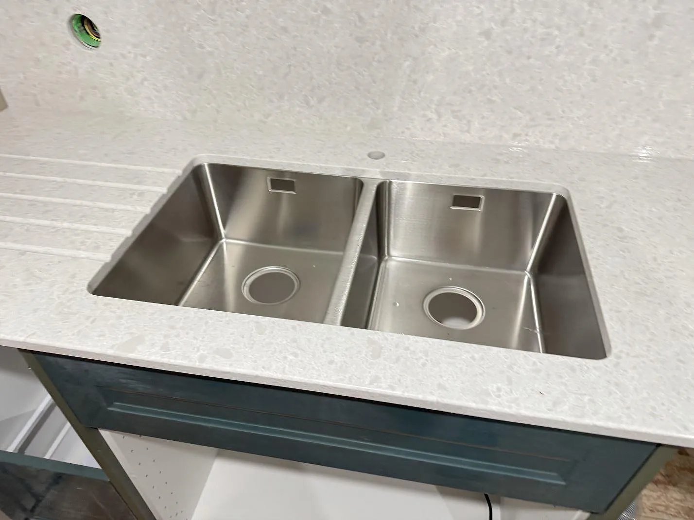Närbild av köksbänkskiva i Technistone Noble Quartzite med dubbel rostfri diskho och ljus polerad komposityta i Staffanstorp.