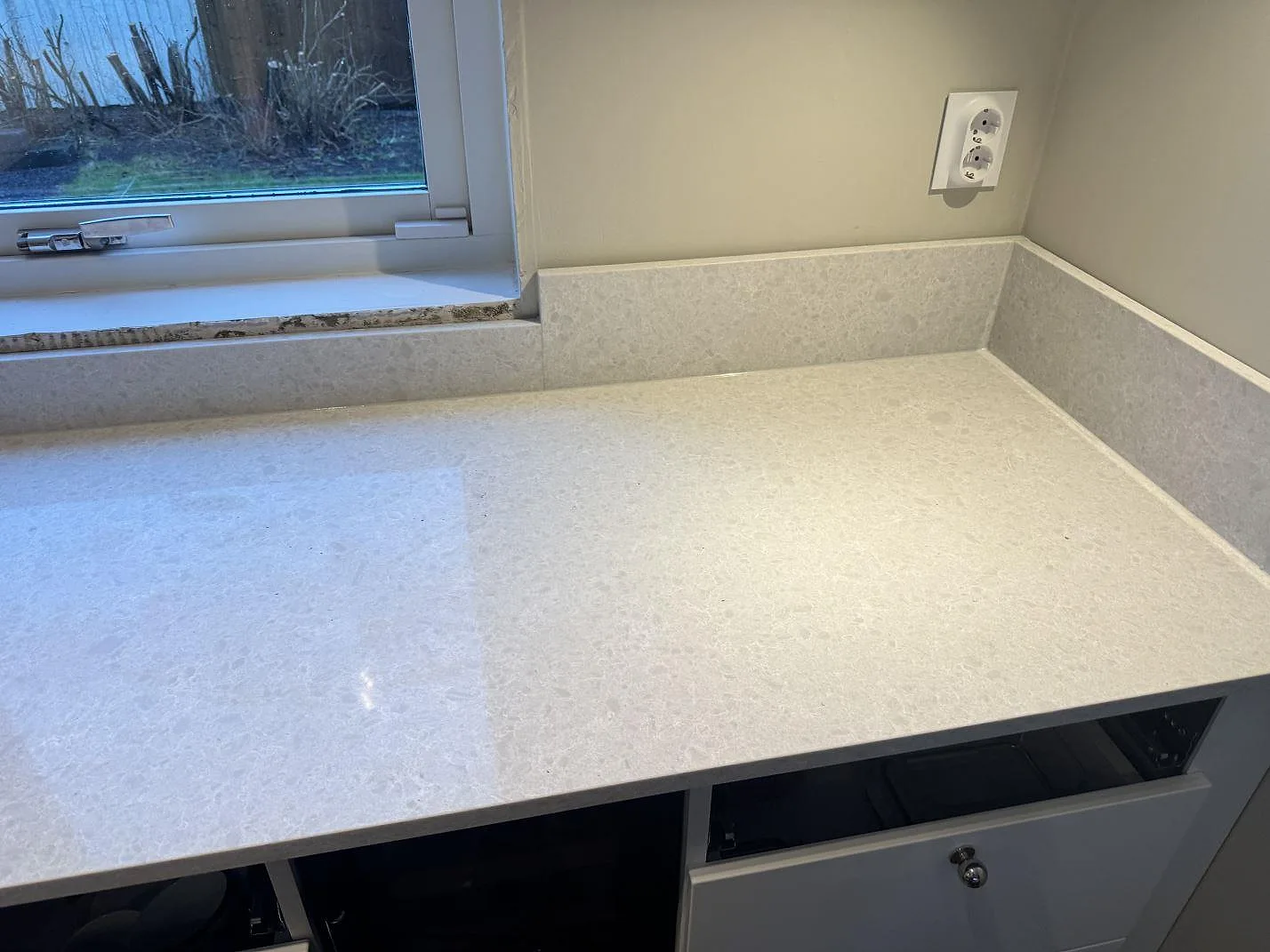 Polerad Technistone Noble Quartzite bänkskiva i komposit under fönster med uppvikt stänkkant i Västra Frölunda.