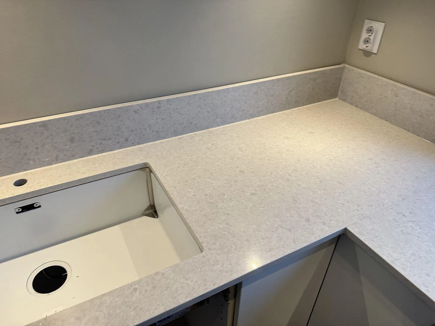 Polerad Technistone Noble Quartzite komposit runt diskhoöppning och hörn med kort stänkskydd i Västra Frölunda.