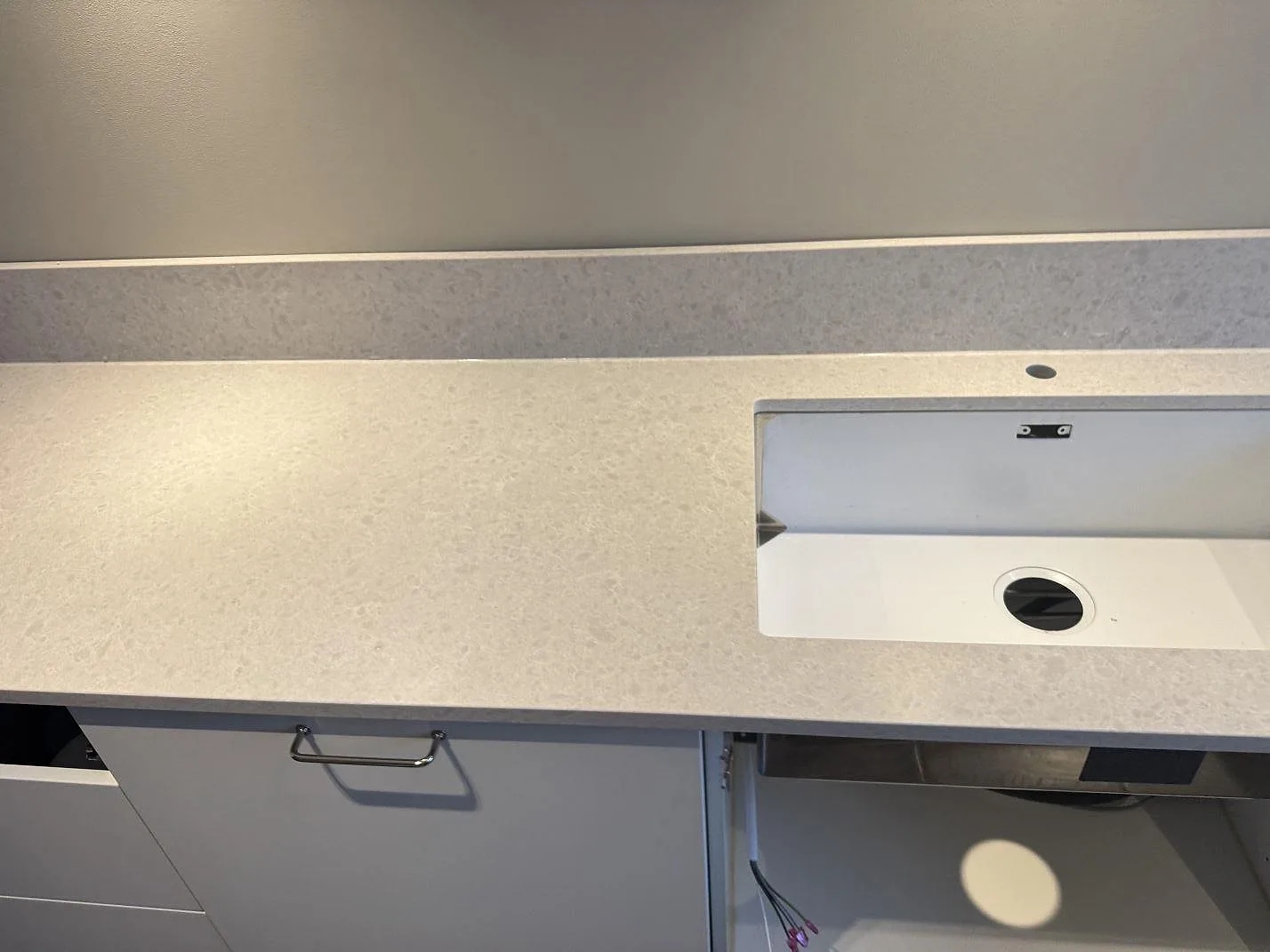 Rak vy över Technistone Noble Quartzite bänkskiva, polerad komposit, med diskhozon och öppen stomme i Västra Frölunda.