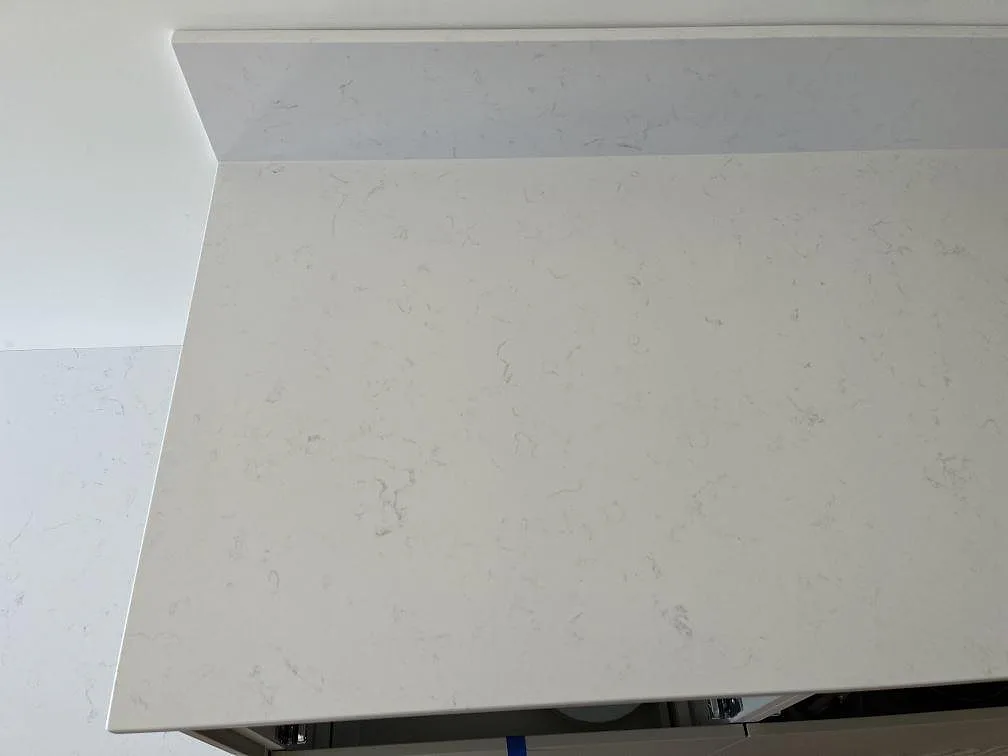 Vit Technistone Noble Supreme White bänkskiva med uppvikt stänkkant sedd ovanifrån i ett kök i Beddingestrand.
