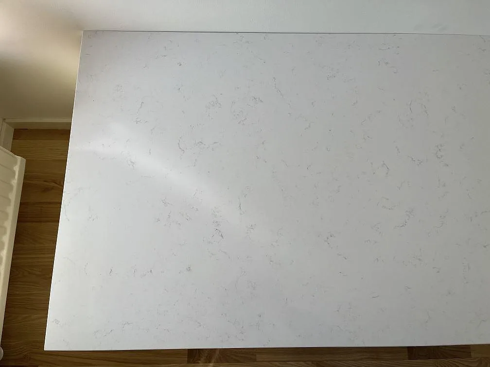 Vit Technistone Noble Supreme White köksö med mjuk grå ådring sedd ovanifrån i ett kök i Beddingestrand.
