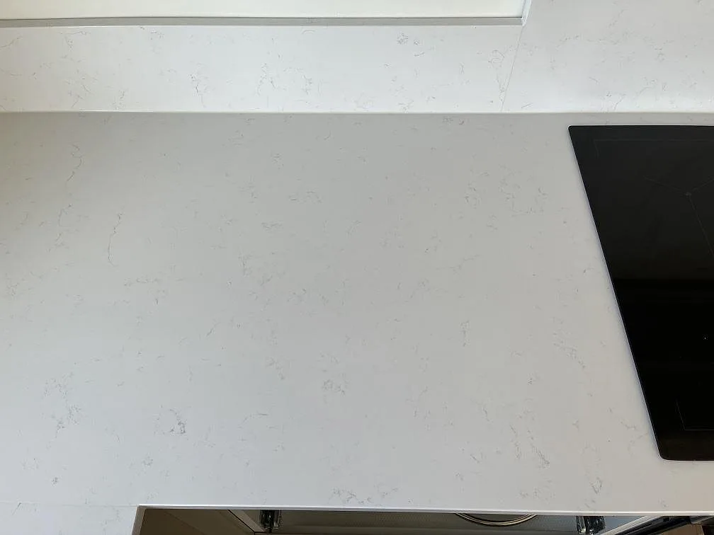 Vit Technistone Noble Supreme White bänkskiva med induktionshällens kant och stänkkant i ett kök i Beddingestrand.
