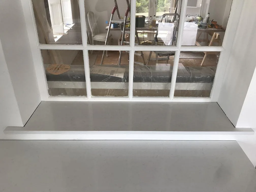 Fönsterbänk i vit Technistone Noble Supreme White och anslutande köksbänk under montering i ett kök i Bjärred.