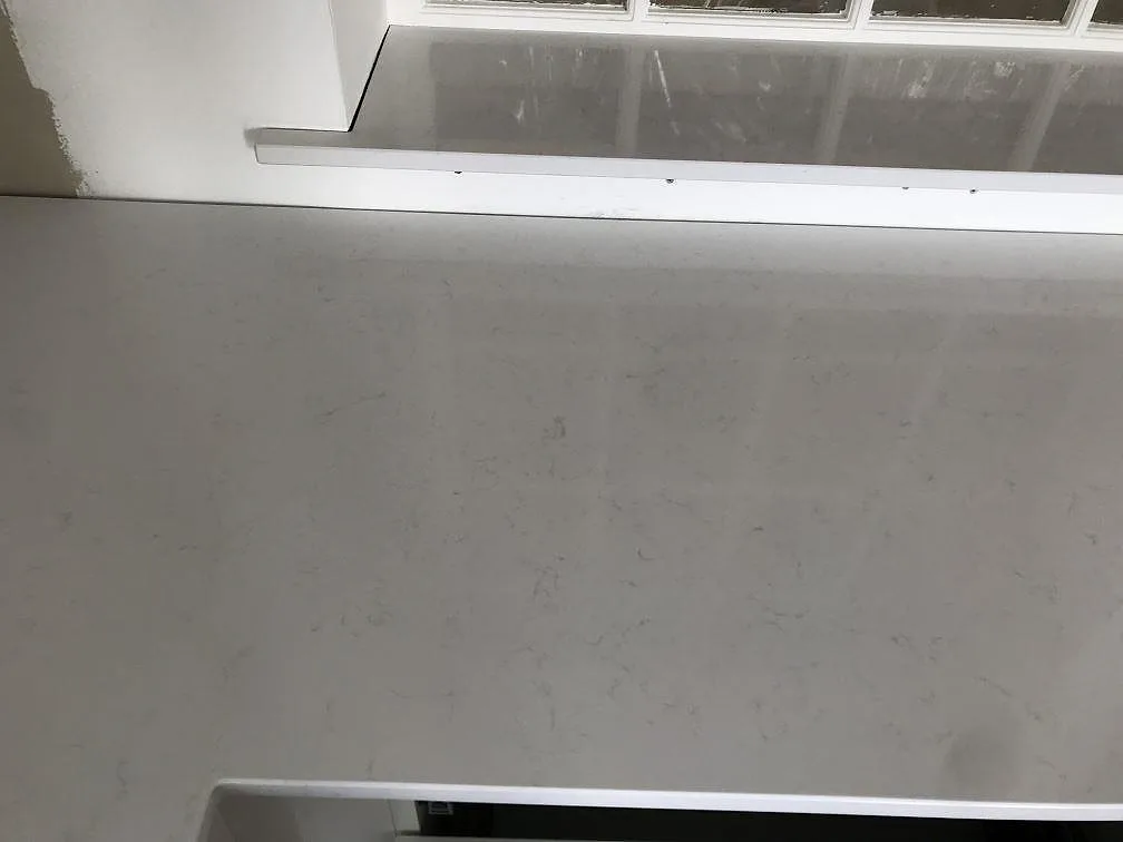 Bänkskiva och fönsterbänk i vit Technistone Noble Supreme White, polerad, med mjuk grå ådring i ett kök i Bjärred.