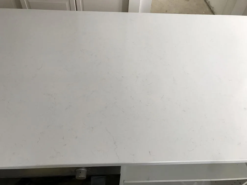 Polerad köksbänkskiva i vit Technistone Noble Supreme White sedd uppifrån med mjuk grå ådring i ett kök i Bjärred.