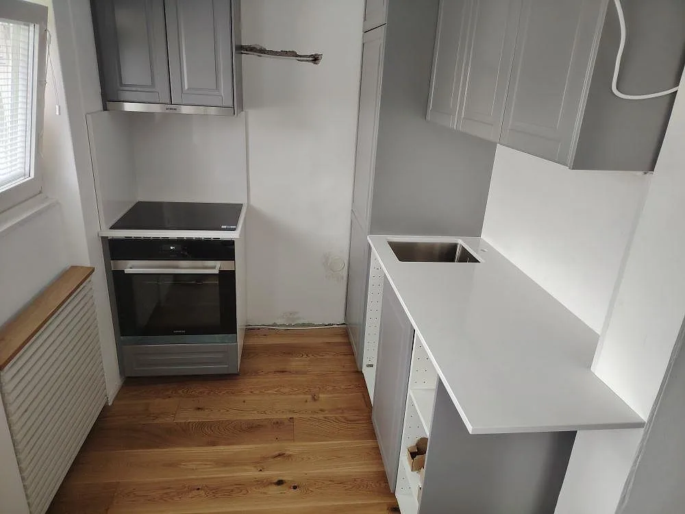 Köksbänkskiva i vit Technistone Noble Supreme White, 20 mm polerad kvartskomposit, med stänkskydd och synlig diskbänksdel i ett kök i danderyd.