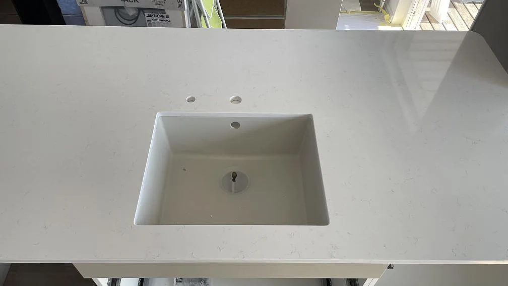 Närbild på rektangulär diskho i en polerad Technistone Noble Supreme White bänkskiva med ljus ådring i Falköping.