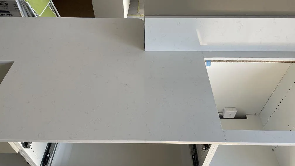 Detalj av Technistone Noble Supreme White bänkskiva i polerad kvartskomposit med låg stänkkant och skarv mot hällzonen i Falköping.