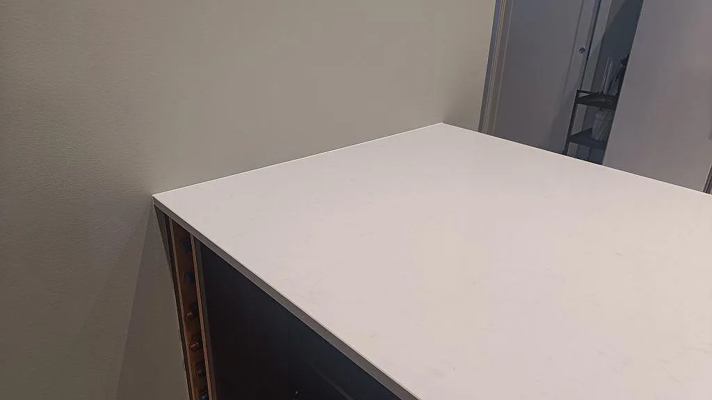 Närbild av hörn och vägganslutning på köksbänkskiva i polerad Technistone Noble Supreme White i Floda.