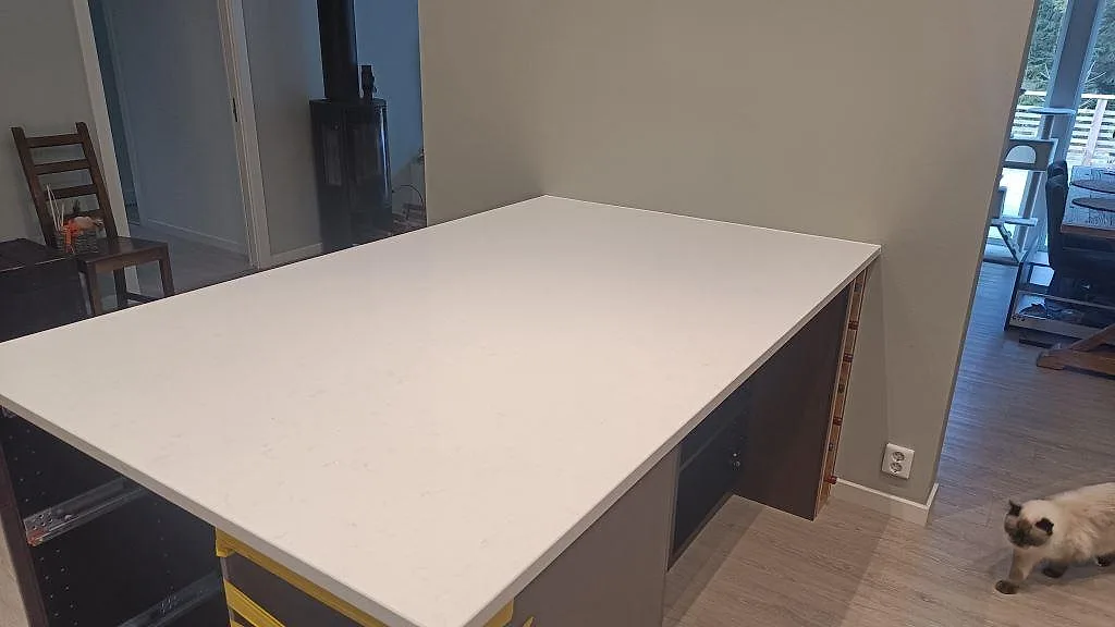 Polerad vit Technistone Noble Supreme White som köksbänkskiva på öppna stommar med diskret grå ådring i Floda.