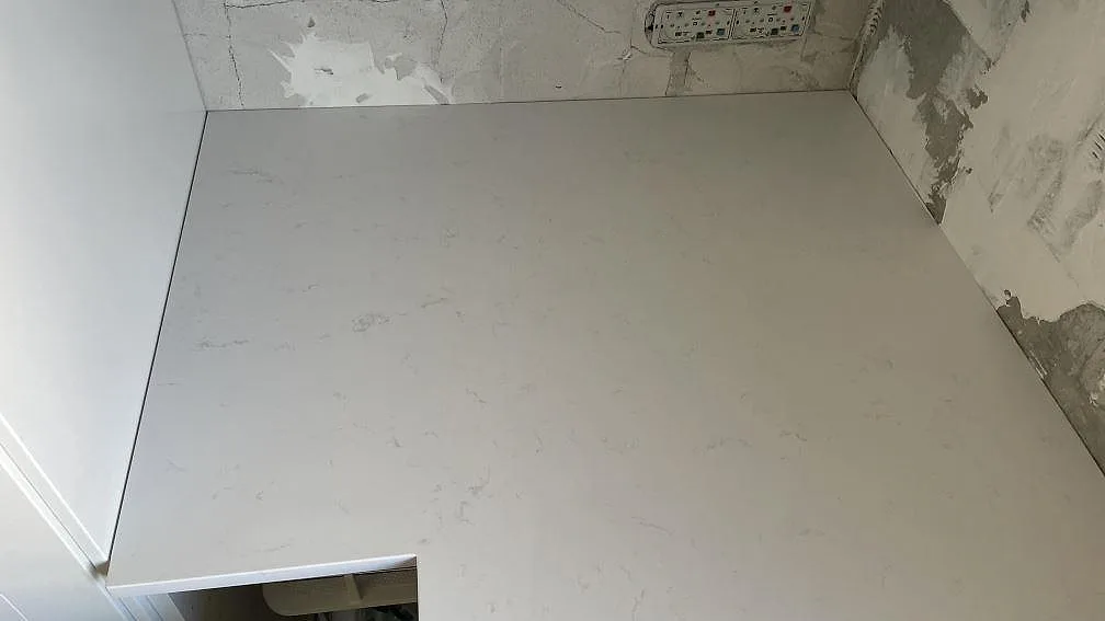 Ovanifrån av en polerad vit köksbänkskiva i Technistone Noble Supreme White med mjuk grå ådring i ett kök i Greve.