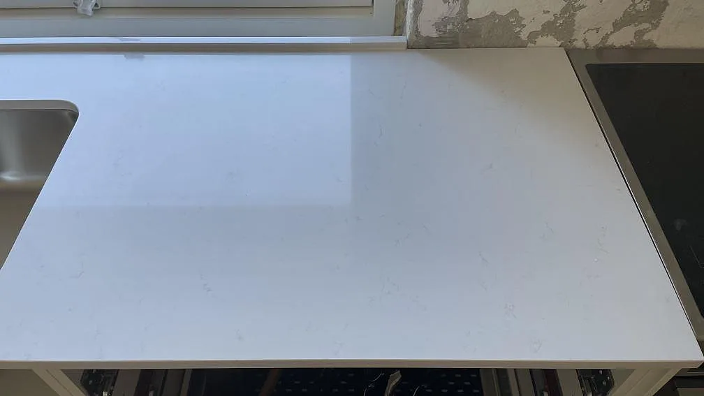 Polerad vit köksbänkskiva i Technistone Noble Supreme White med underlimmad rostfri diskho och induktionshäll i ett kök i Greve.