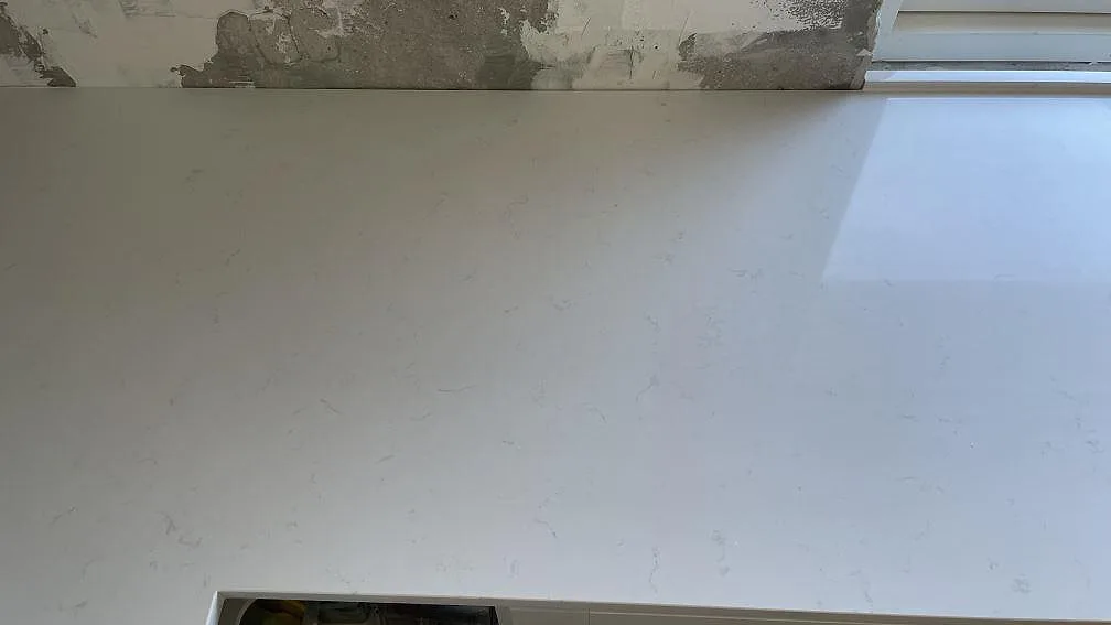 Polerad vit köksbänkskiva i Technistone Noble Supreme White vid ett fönster i ett kök under montering i Greve.