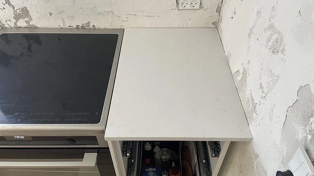 Köksbänkskiva i vit Technistone Noble Supreme White med induktionshäll, polerad yta, i ett kök under montering i Greve.