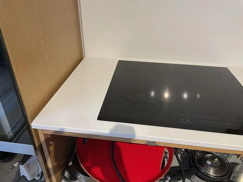Närbild på svart induktionshäll monterad i vit Technistone Noble Supreme White kompositbänkskiva, polerad, i Hässleholm.