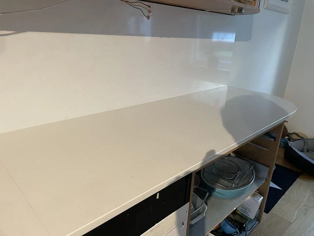 Detalj av polerad Technistone Noble Supreme White köksbänkskiva med rundad avslutning och stänkskydd i ett kök i Hässleholm.