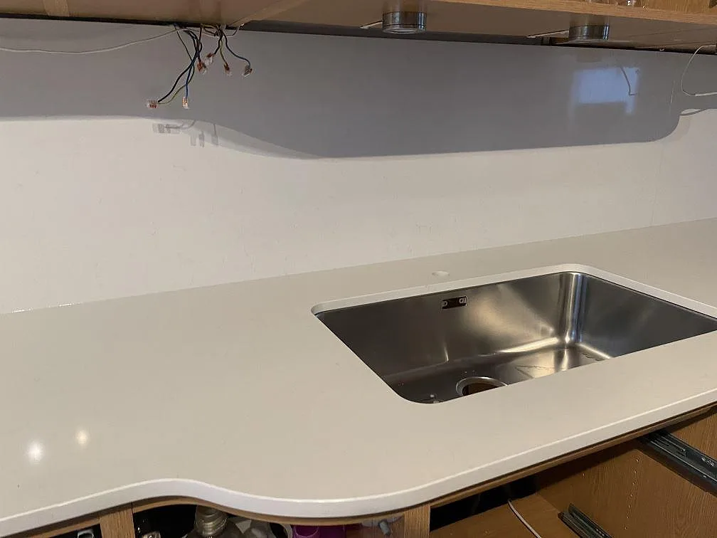 Närbild på vit Technistone Noble Supreme White komposit, polerad, med underlimmad rostfri diskho och låg stänkkant i Hässleholm.