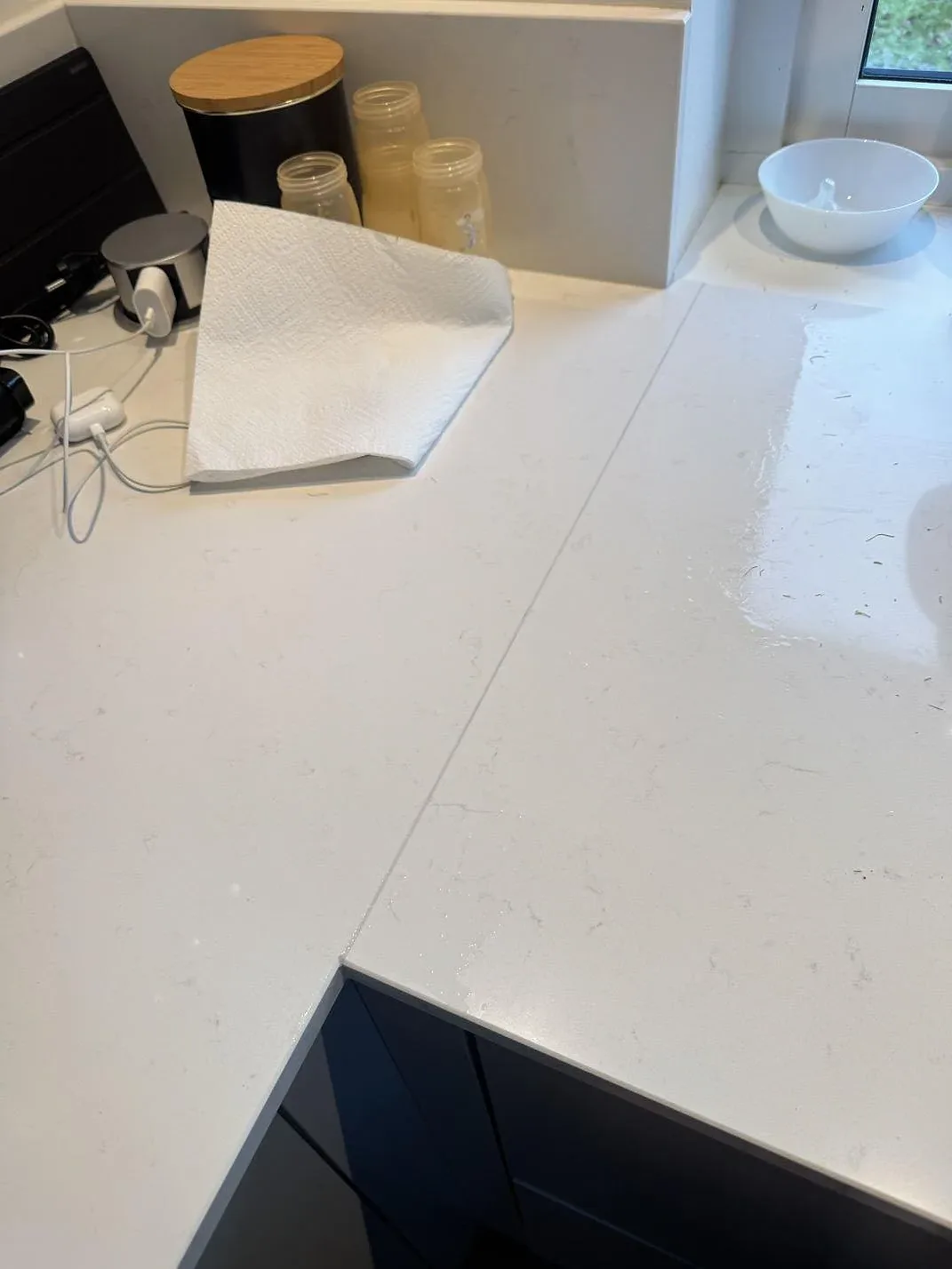 Närbild av ljus polerad Technistone Noble Supreme White köksbänkskiva med diskret grå ådring vid fönster i Höllviken.