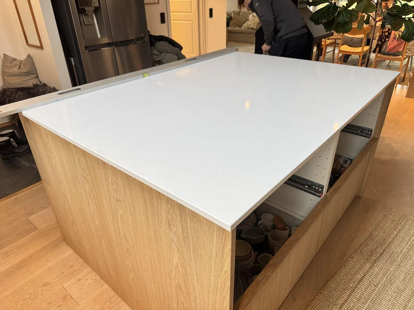 Stor köksö i polerad Technistone Noble Supreme White kvartskomposit över träinredning under montering i Höllviken.