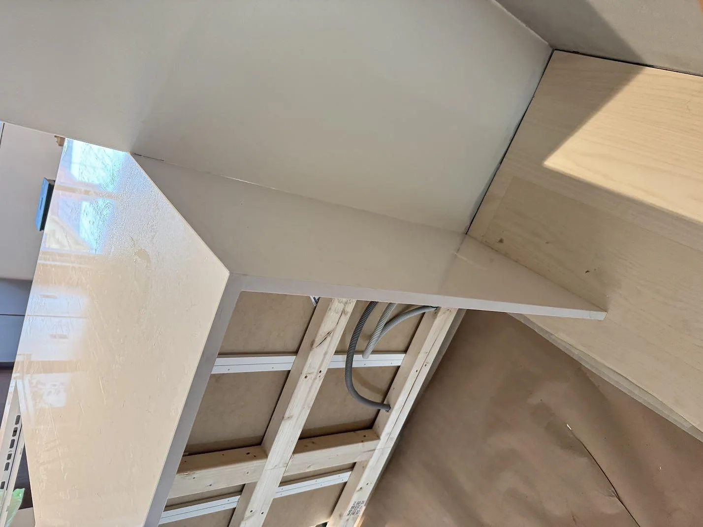 Närbild på vit polerad kompositbänkskiva i Technistone Noble Supreme White vid vägg och öppna installationsstommar i Karlshamn.