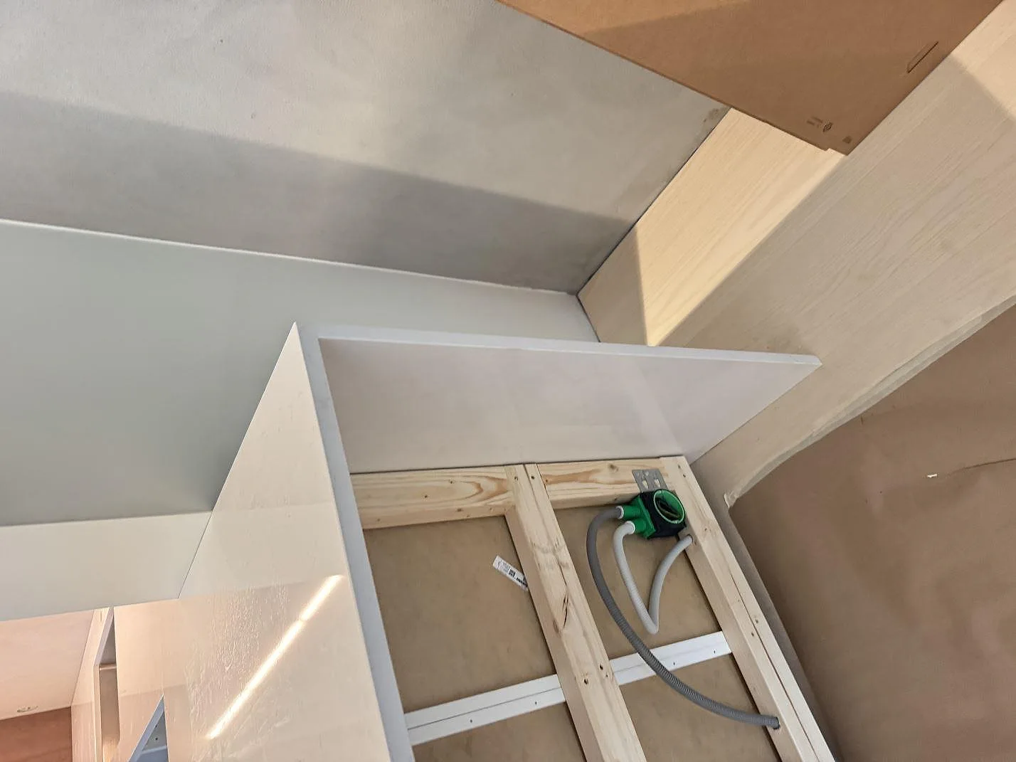 Detaljbild av polerad Technistone Noble Supreme White med passning mot vägg och träinredning under montering i Karlshamn.