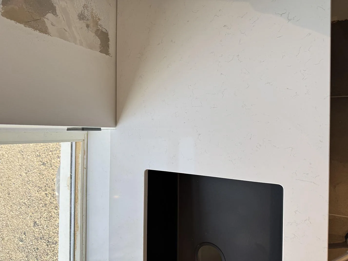 Detalj av polerad Technistone Noble Supreme White runt svart diskho och fönster i ett kök i Klagstorp.