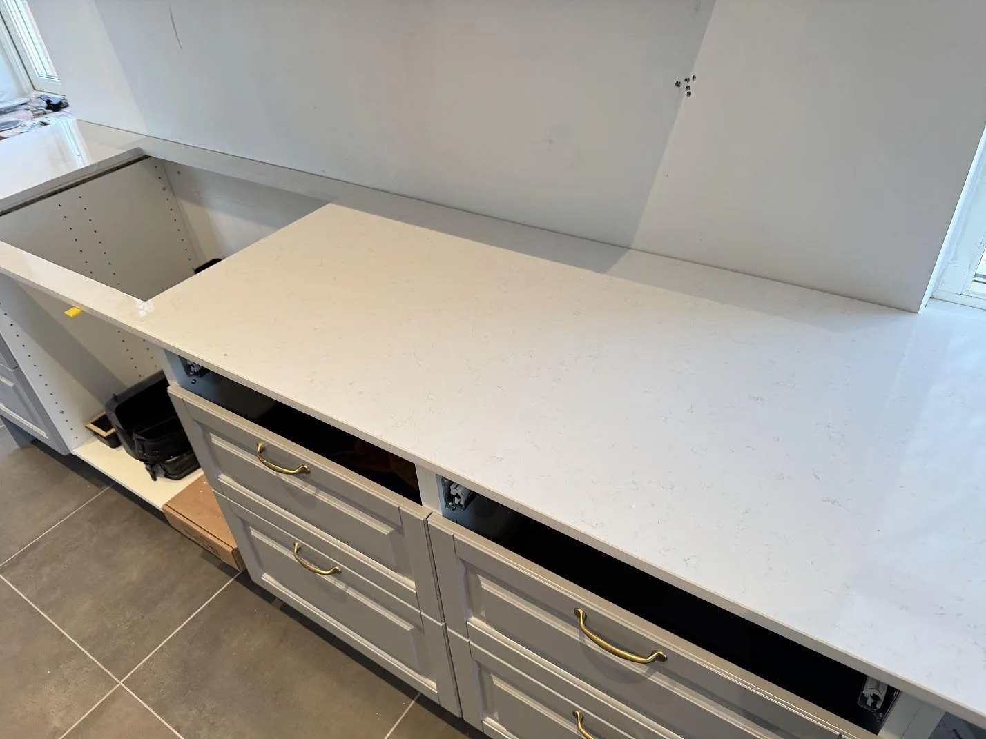 Rak arbetsyta i Technistone Noble Supreme White, polerad komposit, monterad på grå köksskåp i ett kök i Klagstorp.