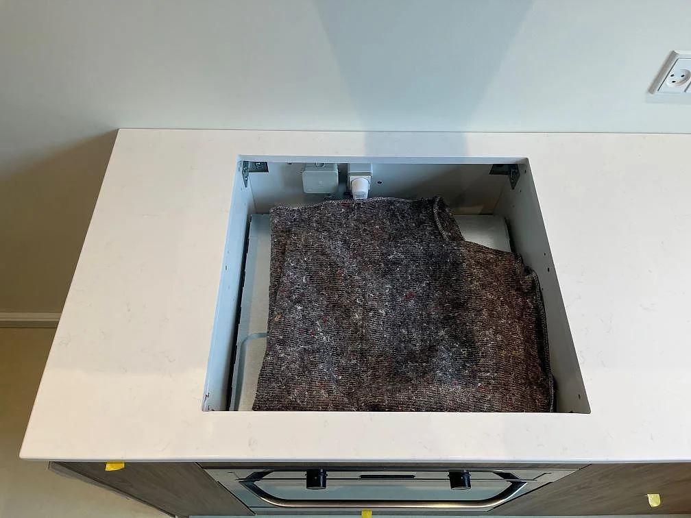 Hälluttag i köksbänkskiva av vit Technistone Noble Supreme White, polerad komposit under montering i København Ø.