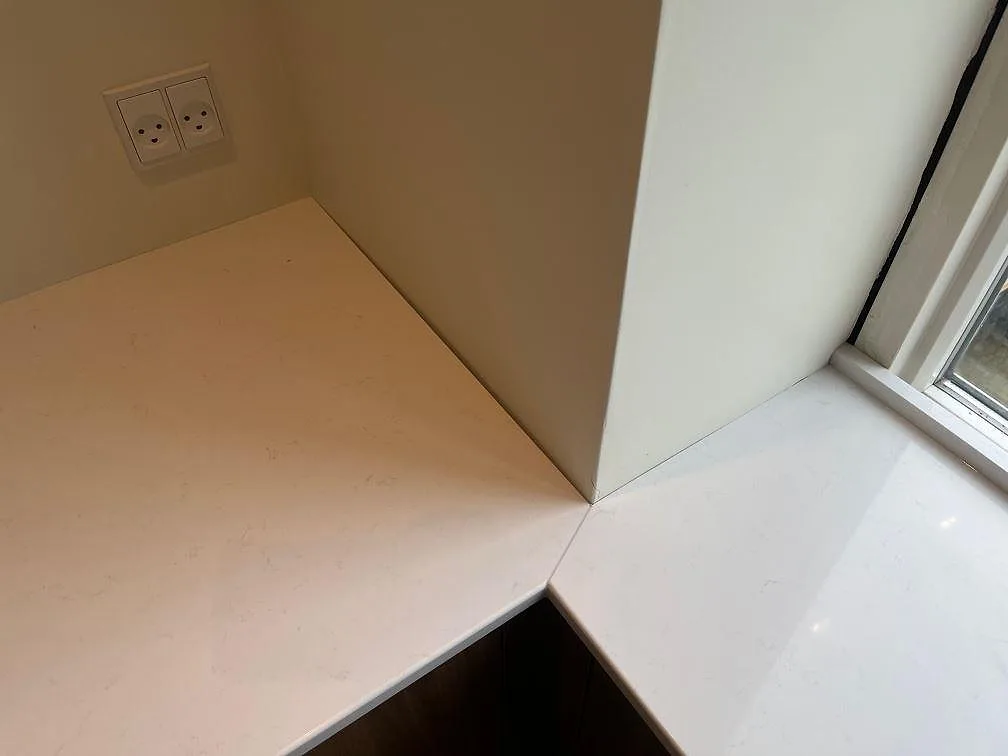 Detalj av hörnskarv och fönsterbänk i polerad Technistone Noble Supreme White i ett kök i København Ø.