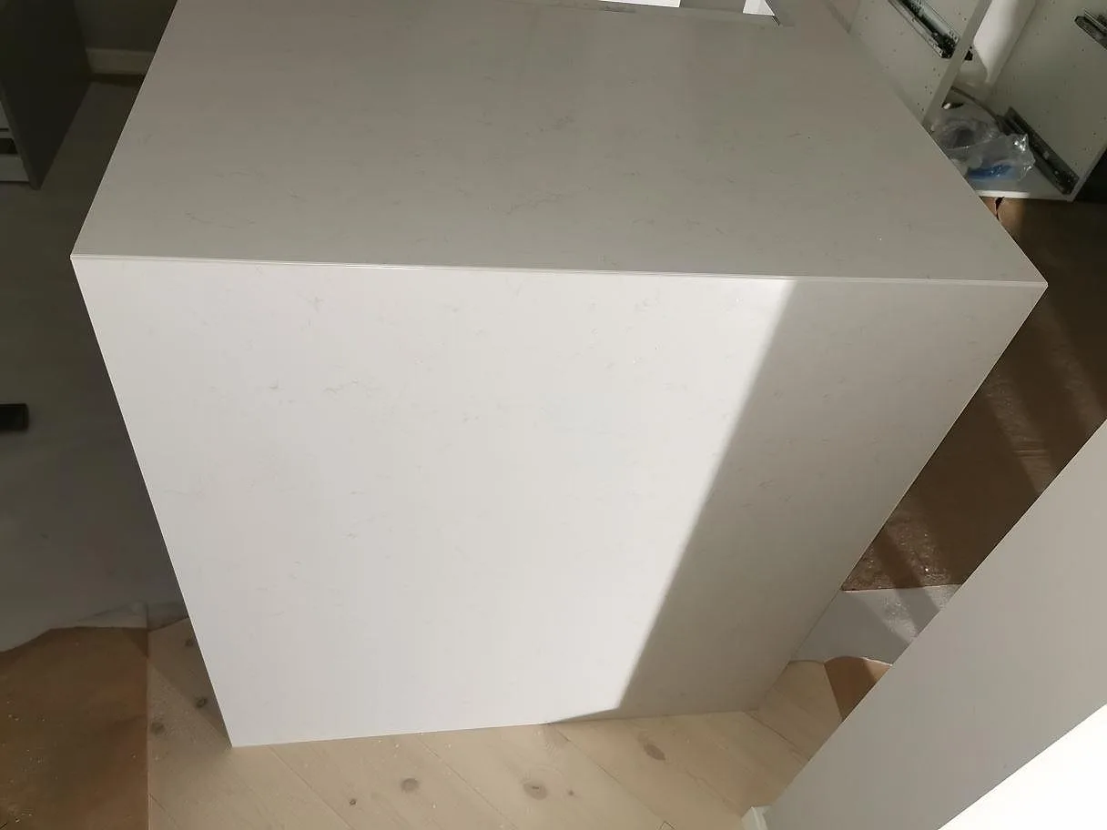Halvö med bänkskiva i vit Technistone Noble Supreme White, polerad, med raka fasade kanter i ett kök i Malmö.