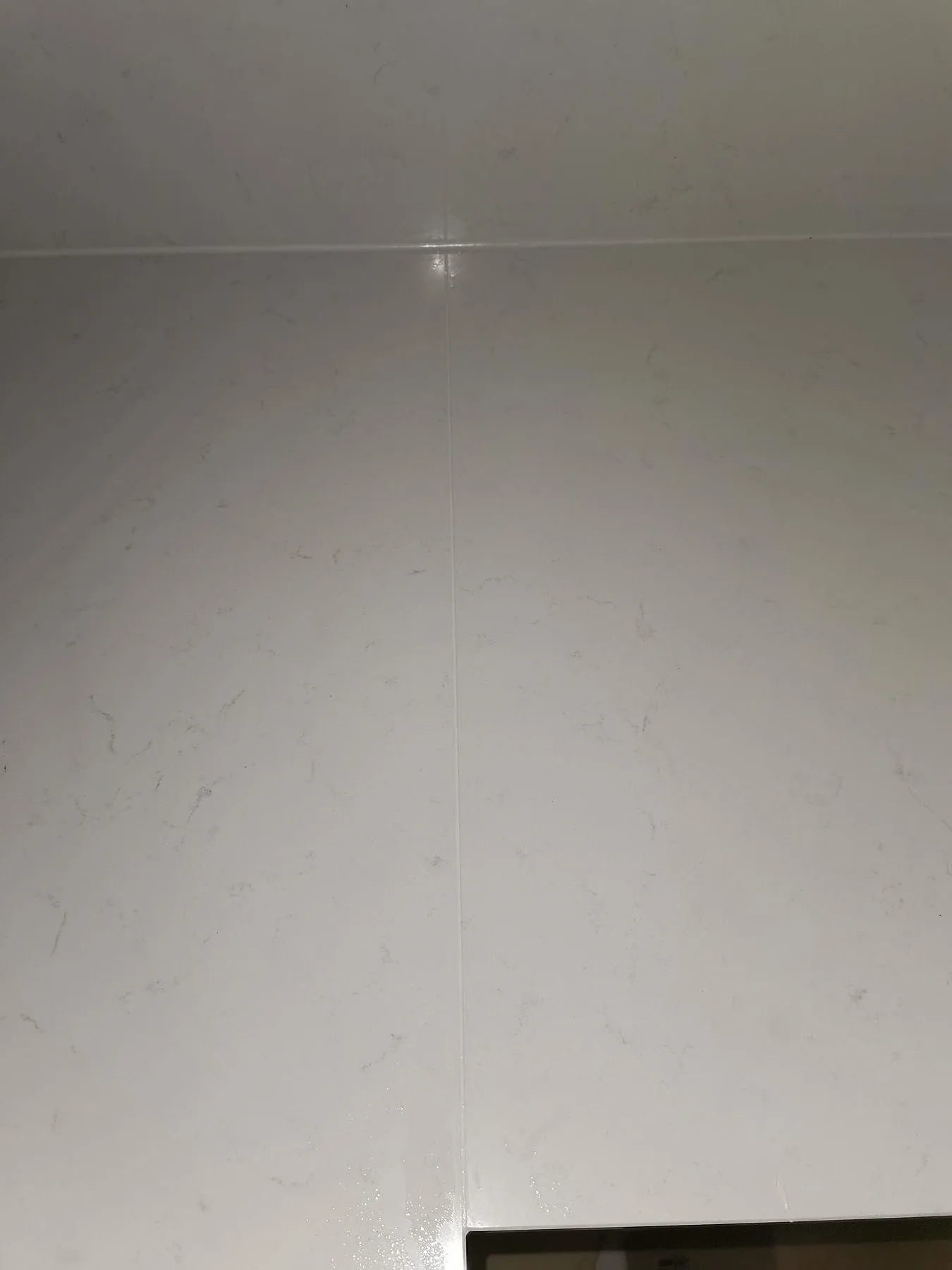 Närbild på den diskreta grå ådringen i vit Technistone Noble Supreme White bänkskiva i ett kök i Malmö.