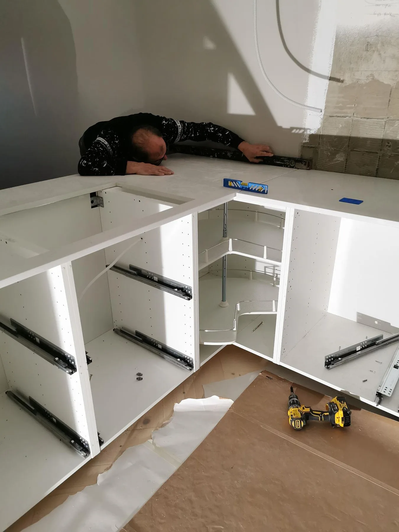 Montör som vattenpassar nyinstallerad bänkskiva i vit Technistone Noble Supreme White på köksstommar i ett kök i Malmö.