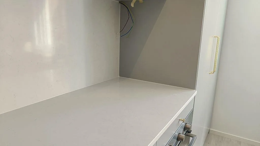 Vit Technistone Noble Supreme White komposityta i en nisch med uppvikt kant i ett kök under montering i Malmö.