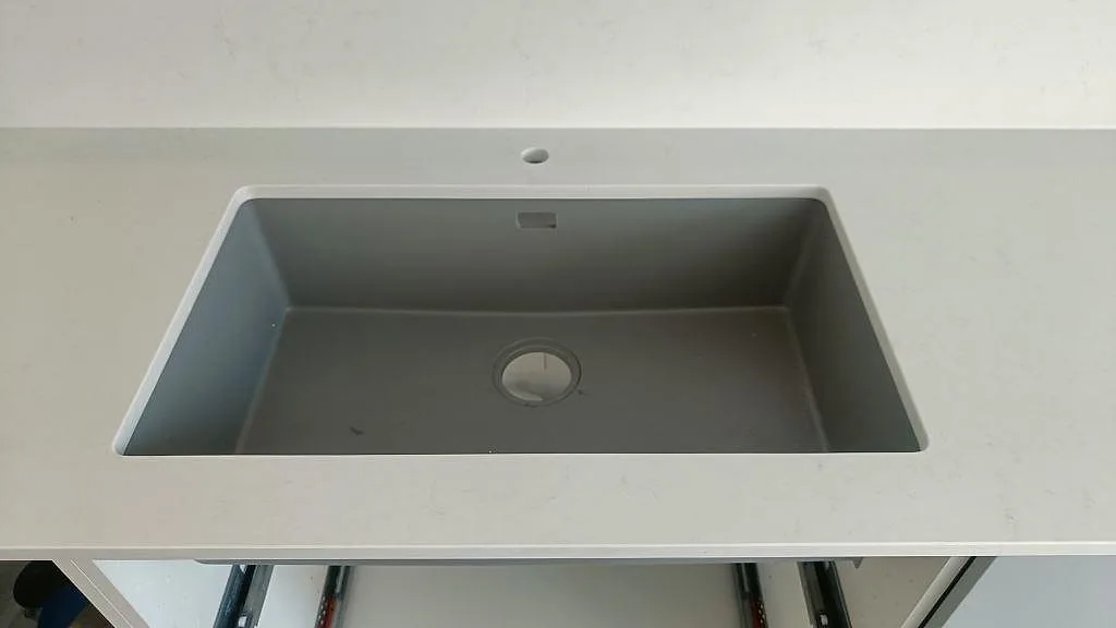 Underlimmad grå kompositdiskho i vit Technistone Noble Supreme White köksbänkskiva med separat blandarhål i Malmö.
