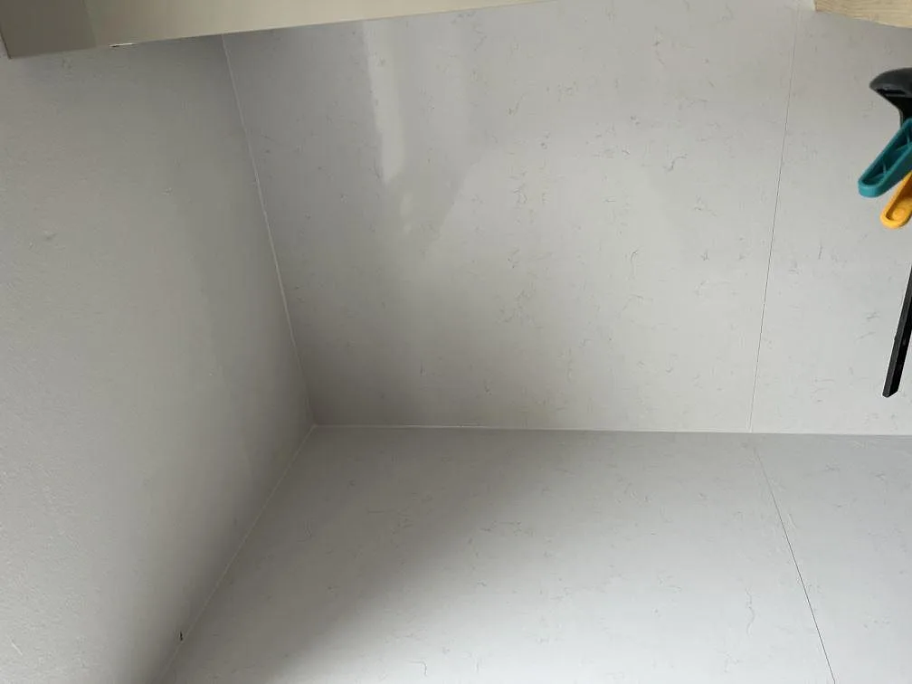 Hörn av polerad vit köksbänkskiva i Technistone Noble Supreme White med stänkskydd i ett kök under montering i Malmö.