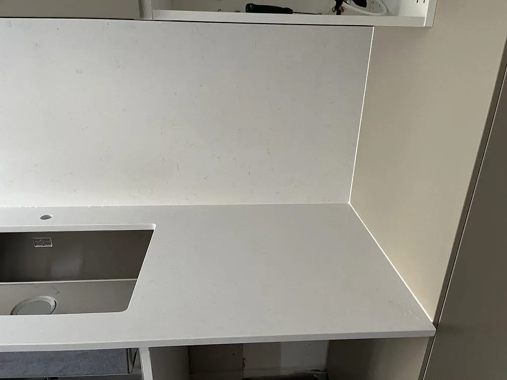 Polerad vit köksbänkskiva i Technistone Noble Supreme White med uppvikt stänkskydd och underlimmad diskho i ett kök i Malmö.