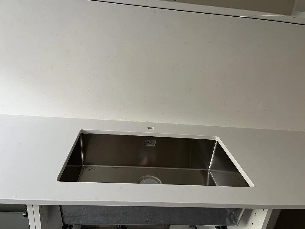 Underlimmad rostfri diskho i polerad vit Technistone Noble Supreme White köksbänkskiva i ett kök i Malmö.