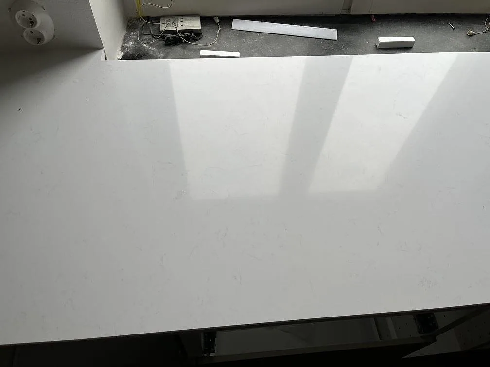 Ovanifrån av polerad vit köksbänkskiva i Technistone Noble Supreme White med diskret grå ådring i ett kök i Malmö.