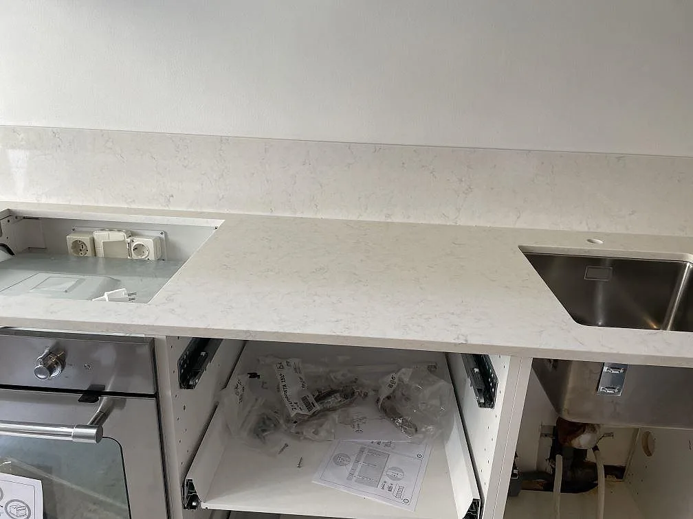 Närbild på polerad Technistone Noble Supreme White som köksbänkskiva med underlimmad rostfri diskho, hällöppning och stänkkant i Malmö.