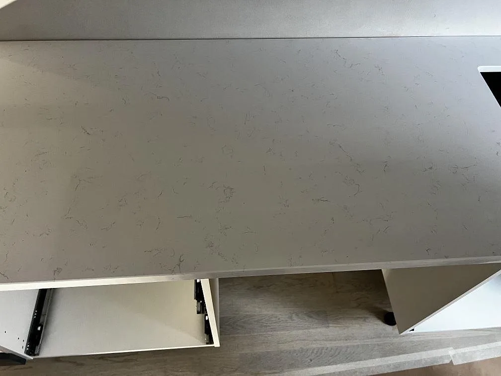 Köksbänkskiva i vit Technistone Noble Supreme White, polerad komposit, på svart köksö under montering i Malmö.